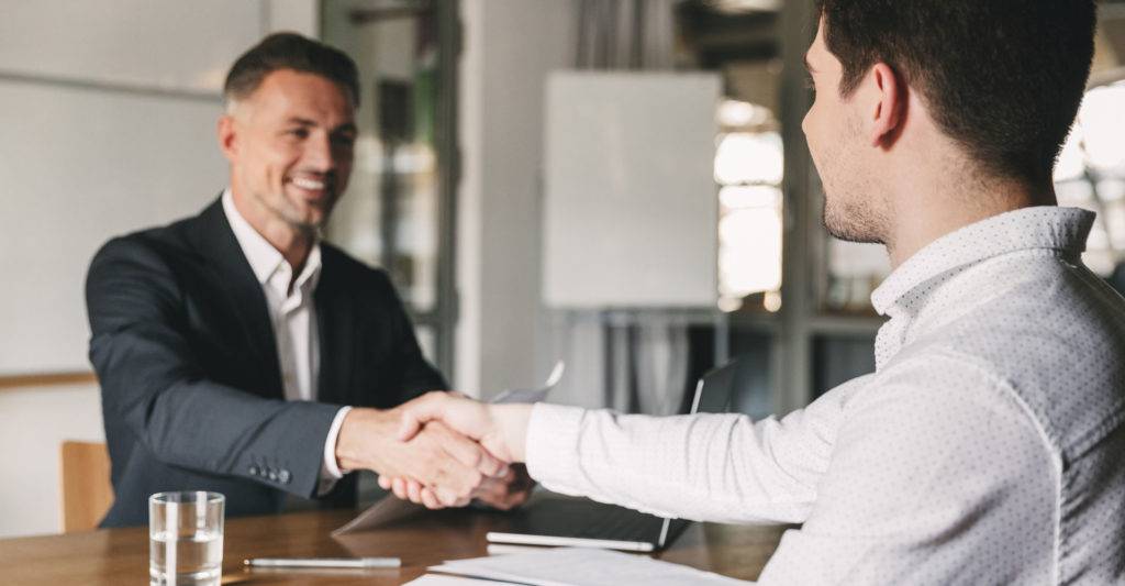 Well-dressed man shaking hands with new employee